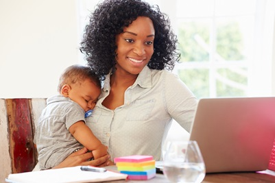 mom on laptop holding sleeping baby