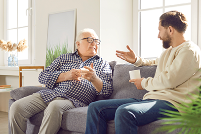 adult son talking to senior dad on couch